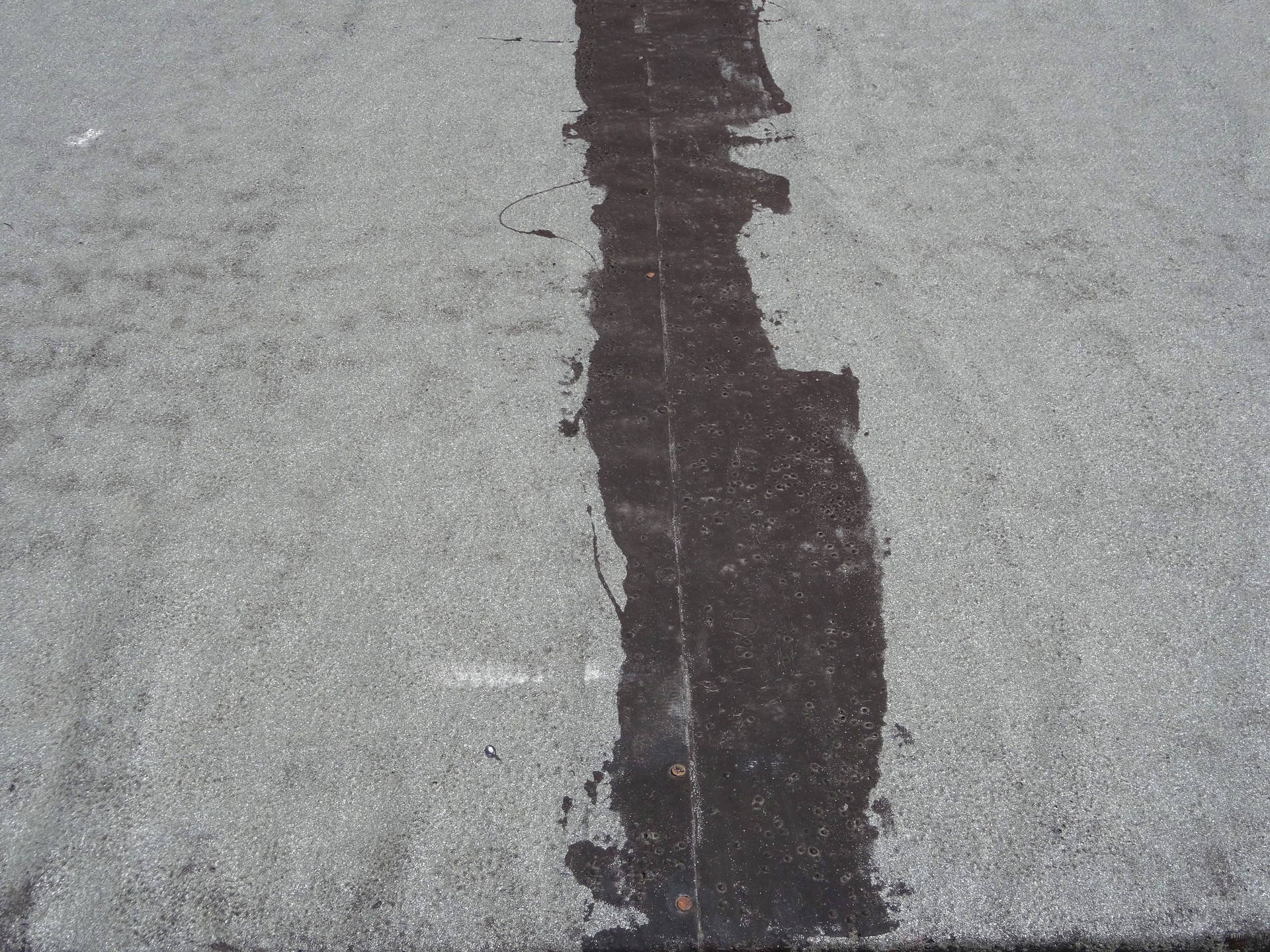 Image of flat roof felt repaired, patched up with tar